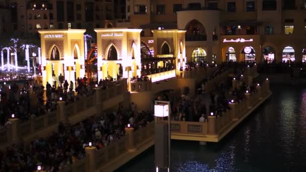 People walk alongside the fountain and Dubai Mall and Burj Khalifa. — Stock Video