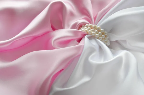 Detalj av draperade vitt och rosa sidentyg med pearl smycken — Stockfoto