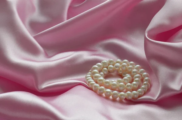 Detalj av draperade rosa sidentyg med pearl smycken — Stockfoto