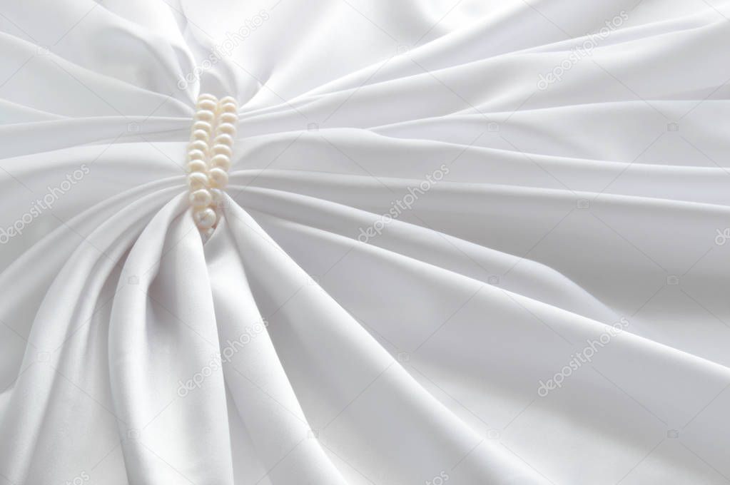 Elegant white background with silk and pearl. Beautiful silk drapes