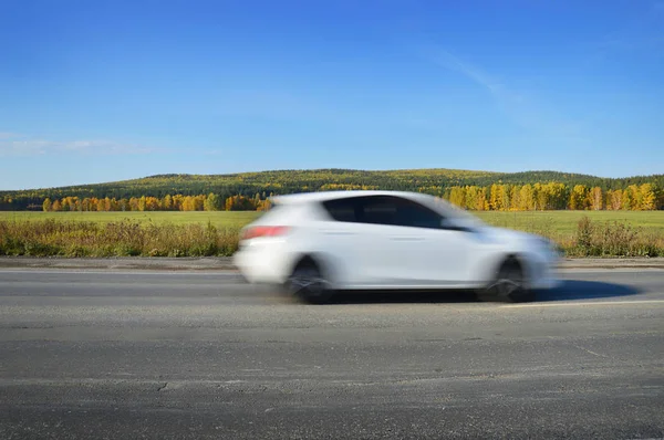 Witte auto rijdt op de weg bij hoge snelheid — Stockfoto