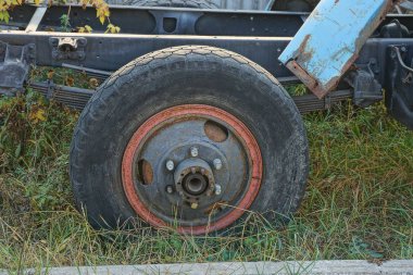 Yeşil çimlerde parçalanmış bir arabada eski bir siyah tekerlek.