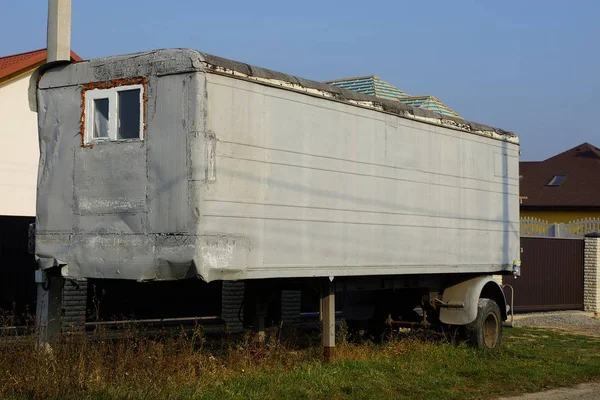 灰色长金属制拖车 窗上有车轮 街道上靠近栅栏的草地上 — 图库照片