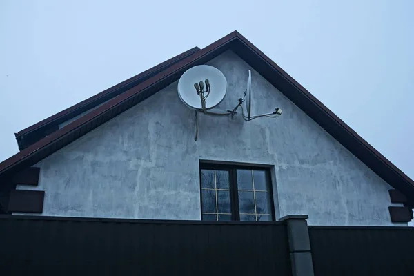 带有窗户和卫星天线的灰色房屋立面在黑色栅栏后面 — 图库照片
