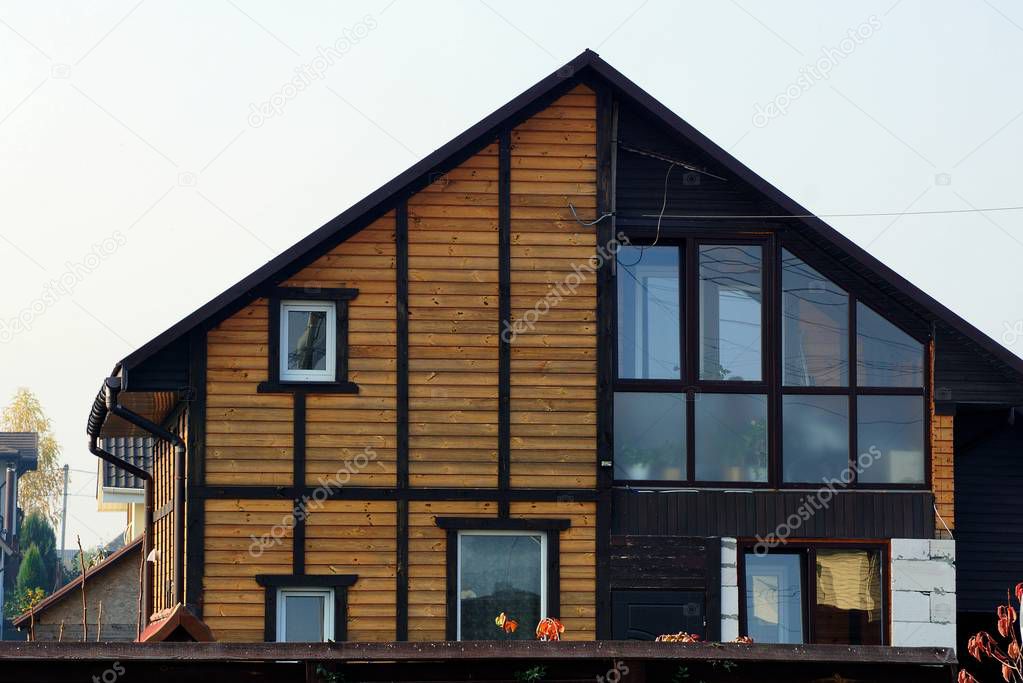 facade of a brown wooden house with windows against the sky