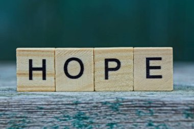 Kelime umudu, yeşil arka plandaki gri bir masanın üzerindeki ahşap harflerden oluşur.