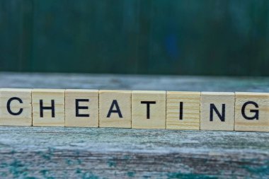 word cheating from brown wooden letters on a gray table