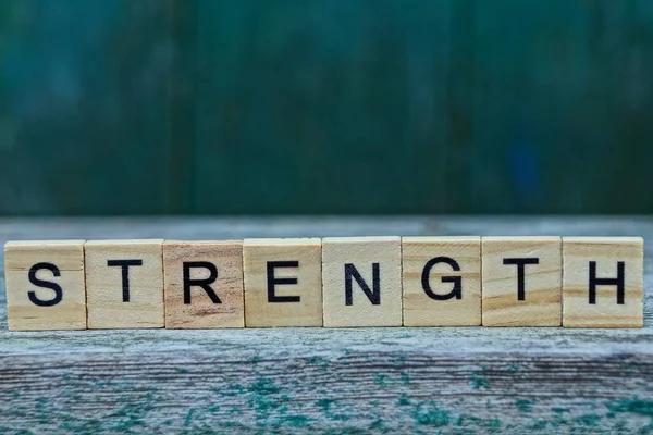 word strength made of brown wooden letters on a gray table