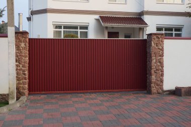  Kırsal bir sokakta büyük kırmızı metal bir kapı ve çit.