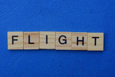 Mavi masadaki kahverengi ahşap harflerden yapılmış kelime uçuşu.