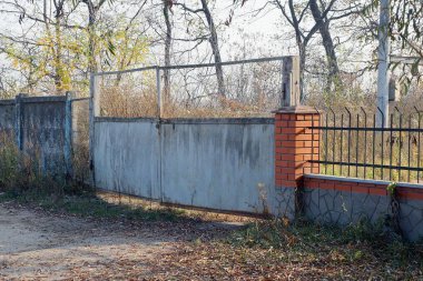 Eski gri kapalı metal kapı ve kırsal bir sokakta çitin bir kısmı