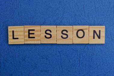 Mavi masadaki kahverengi ahşap harflerden alınan kelime dersi.