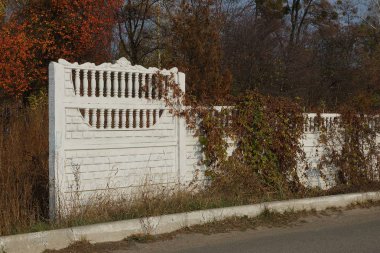 Uzun beyaz beton çitler, caddelerde kurumuş bitki örtüsüyle kaplı.