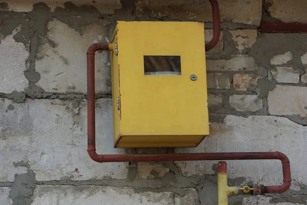 Yellow metal box with gas meter and brown pipe on a gray wall — Stock Image Yellow Metal Box Gas Meter Brown Pipe Gray Wall Royalty Free Stock Photos