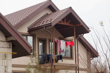 Gökyüzüne karşı özel bir evin ön cephesinde açık kahverengi ahşap balkon.