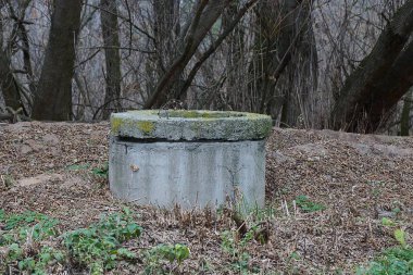 Eski gri beton kanalizasyon kuru çimlerde duruyor 