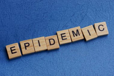 Kahverengi ahşap harflerden oluşan salgın sözcüğü mavi bir masada yatıyor.