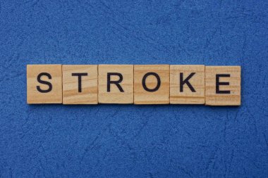 Kahverengi ahşap harflerden yapılmış kelime vuruşu mavi bir masada yatıyor.