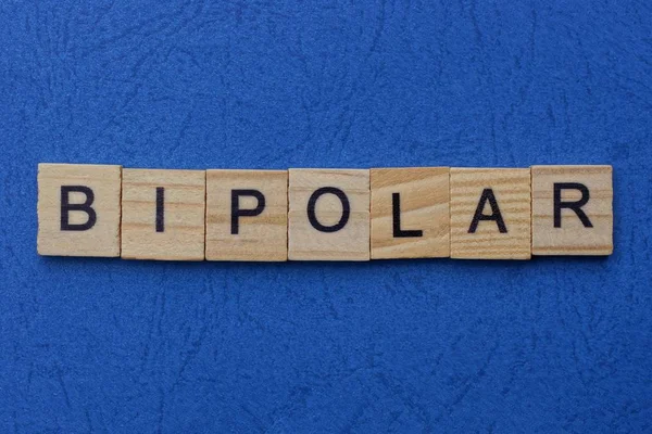 Wort Bipolar Aus Braunen Holzbuchstaben Liegt Auf Einem Blauen Tisch — Stockfoto