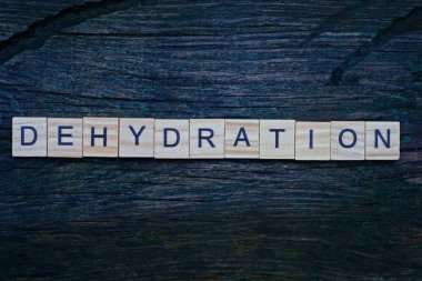 Kahverengi ahşap harflerden yapılan susuzluk kelimesi gri bir masada yatıyor.