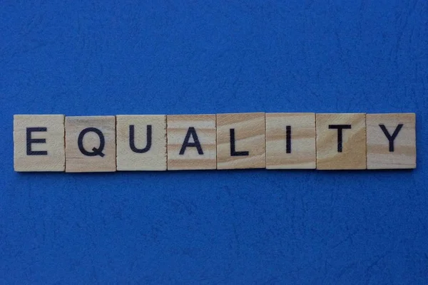 灰色の木製の文字で作られた単語の平等は青い背景にあります — ストック写真