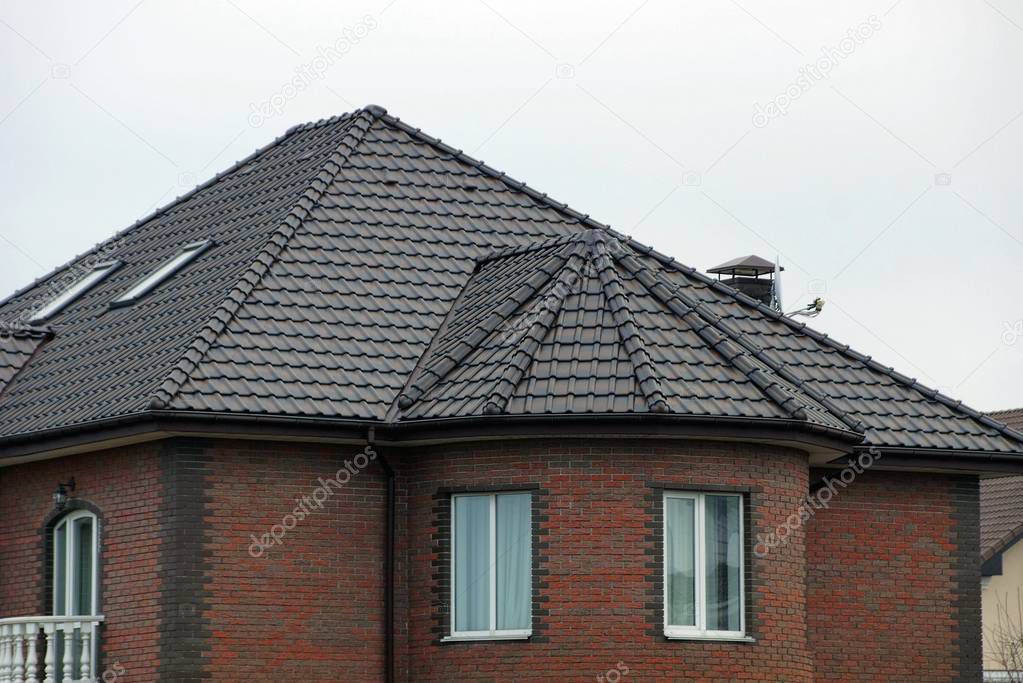 brick house facade with windows under a brown tiled roof 