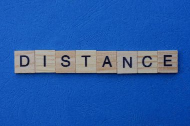 Kelime uzaklığı gri ahşap harflerden yapılır mavi bir arka planda yatar