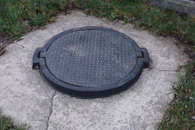 Siyah demir kapak kanalizasyonda Gri betonla caddede