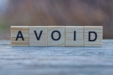 Sözcük, gri bir masada duran tahta harflerden kaçınır.