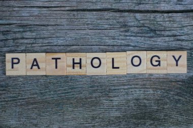 Tahta harflerden yapılmış kelime patolojisi gri bir masada yatıyor.