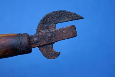 Eski paslı konserve açacağı. Kahverengi ahşap saplı. Mavi arka planda.