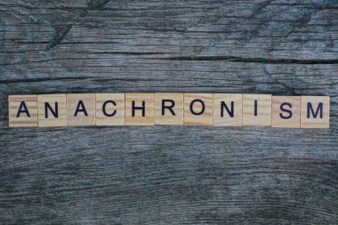 Tahta harflerden yapılan anakronizm kelimesi gri bir arka planda yatar.