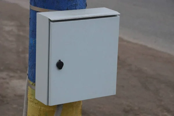 灰色の金属製の電気ボックスが通りのコンクリート製の柱にかかっています — ストック写真
