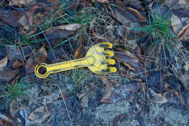 Plastik, sarı tırmık oyuncağı yerde ve bitki örtüsü doğada yatıyor.