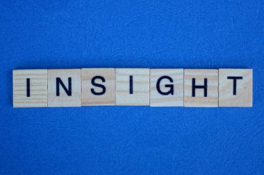 Mavi masadaki küçük tahta harflerden gelen gri bir kavrayış.