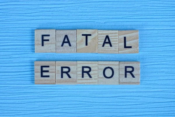 phrase fatal error made from gray wooden letters lies on a blue background