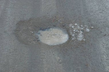 Asfalt yolda çukur olan bir çukur. Su buzlu ve karlı.