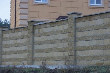 Kırsal bir sokakta, kuru çimenlerin üzerinde uzun, kahverengi tuğlalardan oluşan özel bir duvar.