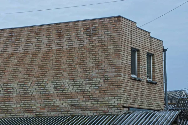 灰色の空に向かって通りに窓のある茶色のレンガ造りの家の一部です — ストック写真