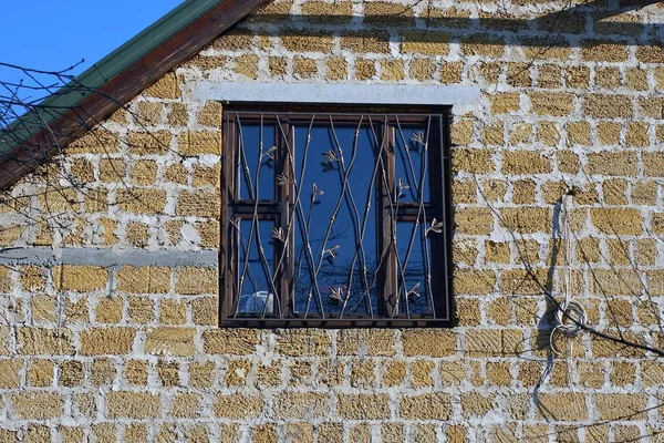 晴れた日に民家の茶色のレンガの壁の鉄の棒の後ろに大きな窓が一つ — ストック写真