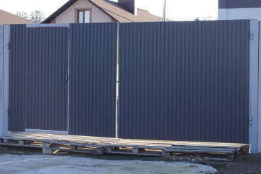 Büyük gri metal kapı ve sokaktaki çitin bir kısmı