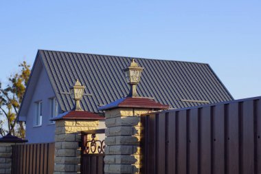 iki gri metal fener kahverengi tuğlalı bir sütun ve caddede metal bir çit