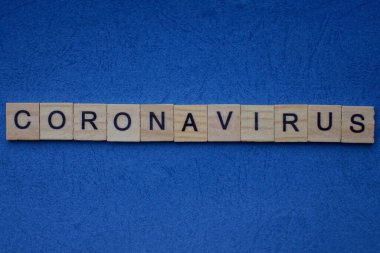 Mavi masadaki küçük ahşap harflerden gelen gri kelime koronavirüs.