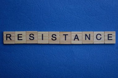 Mavi masadaki küçük tahta harflerden gelen gri kelime direnci.