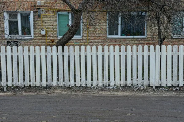 街上一座砖褐色房子前的白色长栅栏 是用木板做的 — 图库照片