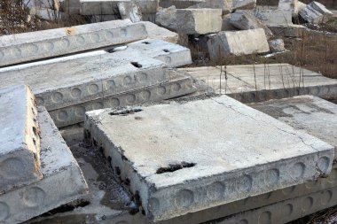 Eski gri beton levhalar kuru çimenlerde yatıyor.