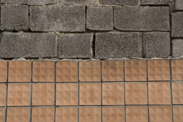 texture of brown old square tiles and gray bricks in the wall of the house