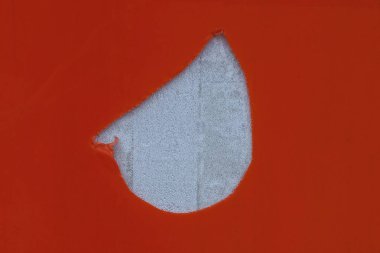 Beyaz beton duvarında büyük bir delik olan kırmızı plastik.