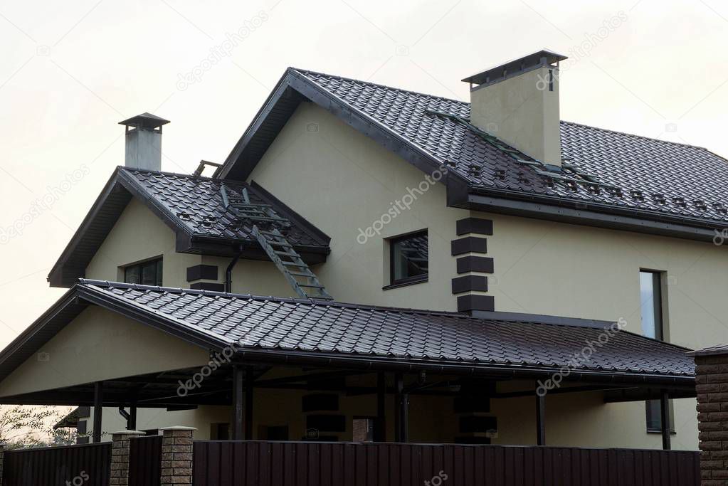 facade of a private house with windows on a gray wall under a brown tiled roof