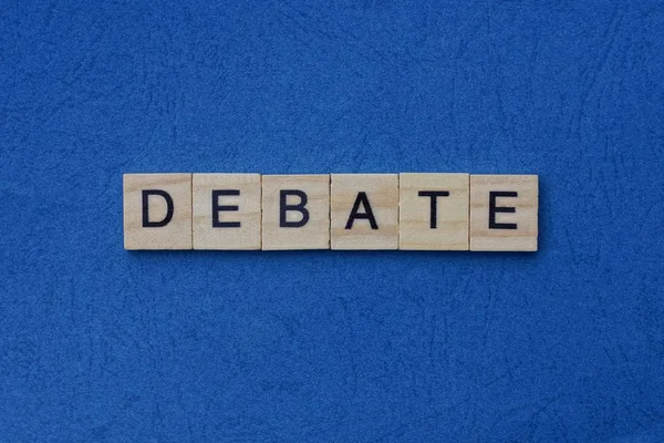 蓝色桌子上的小木制字母中的灰字辩论 — 图库照片